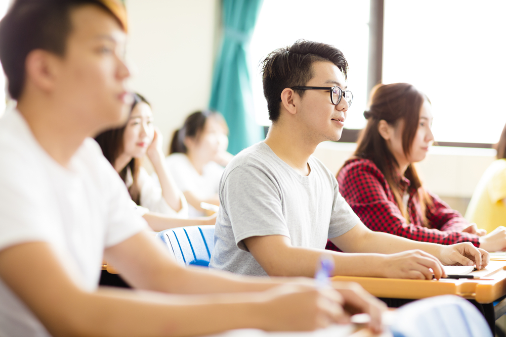 smiling male college student sitting  with classmates